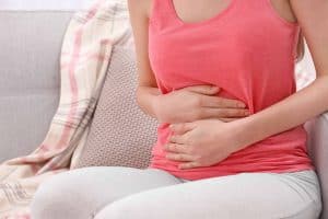 woman sitting on couch holding stomach