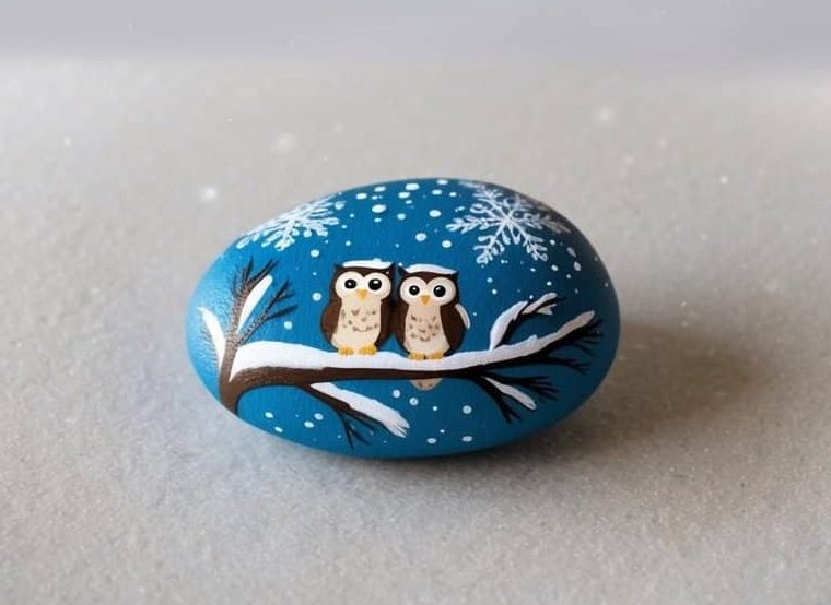 Six cartoon owls sit on a snowy branch above, while a painted rock below shows two owls on a branch, all set against a winter background with snowflakes.