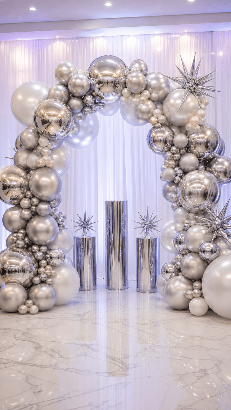 Silver balloon arch with pearlescent and chrome balloons in varying sizes and tiny LED lights creating a nebula-inspired, starlit party entrance.