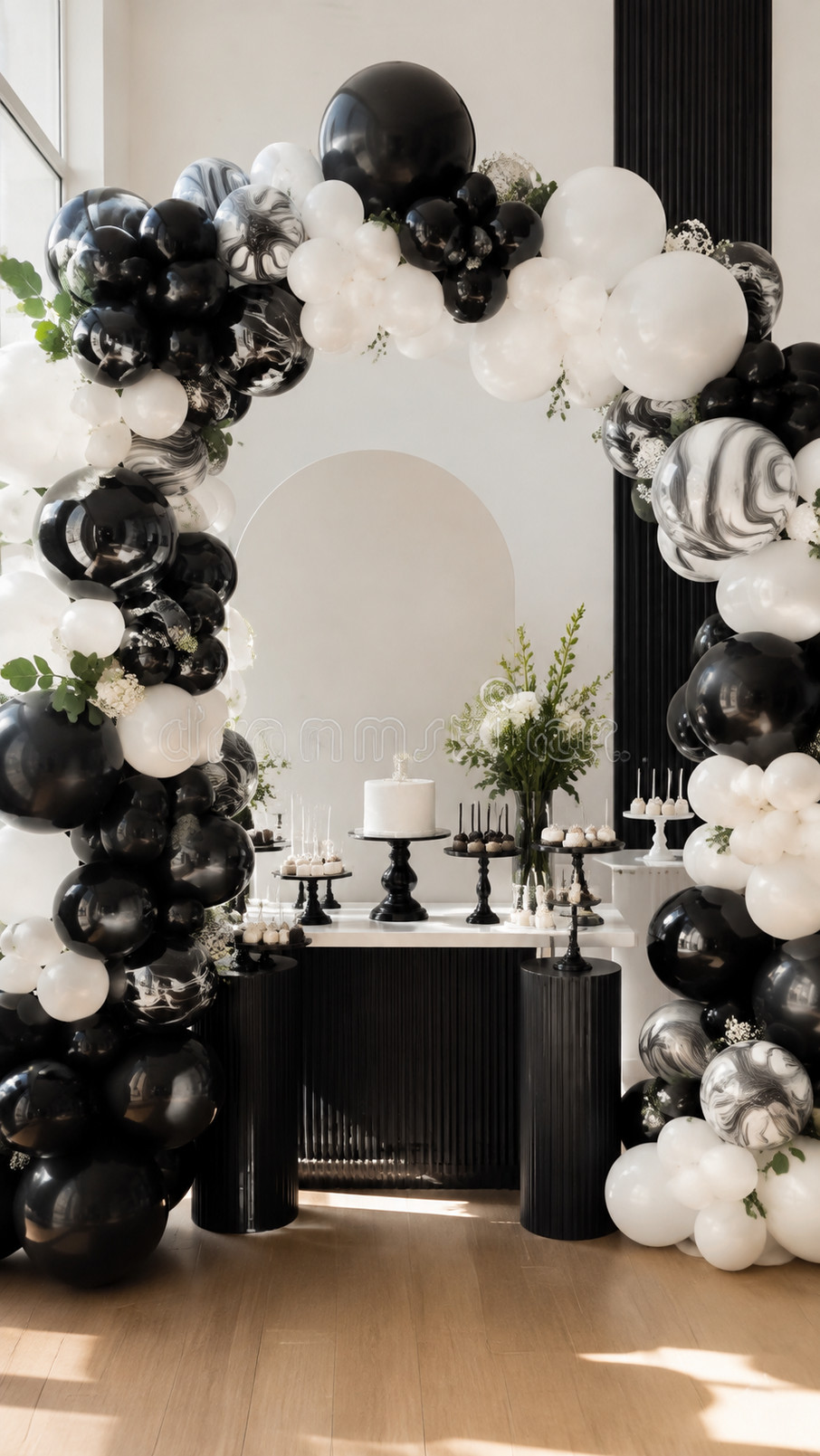 Black and white balloon arch arranged in a dramatic crescent shape with glossy balloons and subtle silver accents.