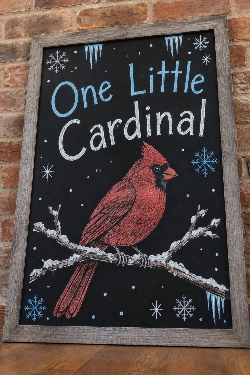 Big Cardinal Drawing Board: a framed winter chalkboard sign reading "One Little Cardinal", hand-drawn in chalk with one large cardinal perched on a snowy branch, filling most of the board.