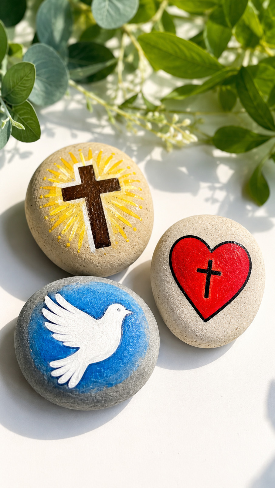 A cream-colored Christian painted rock with blue scripture lettering and small golden stars beside a Bible.