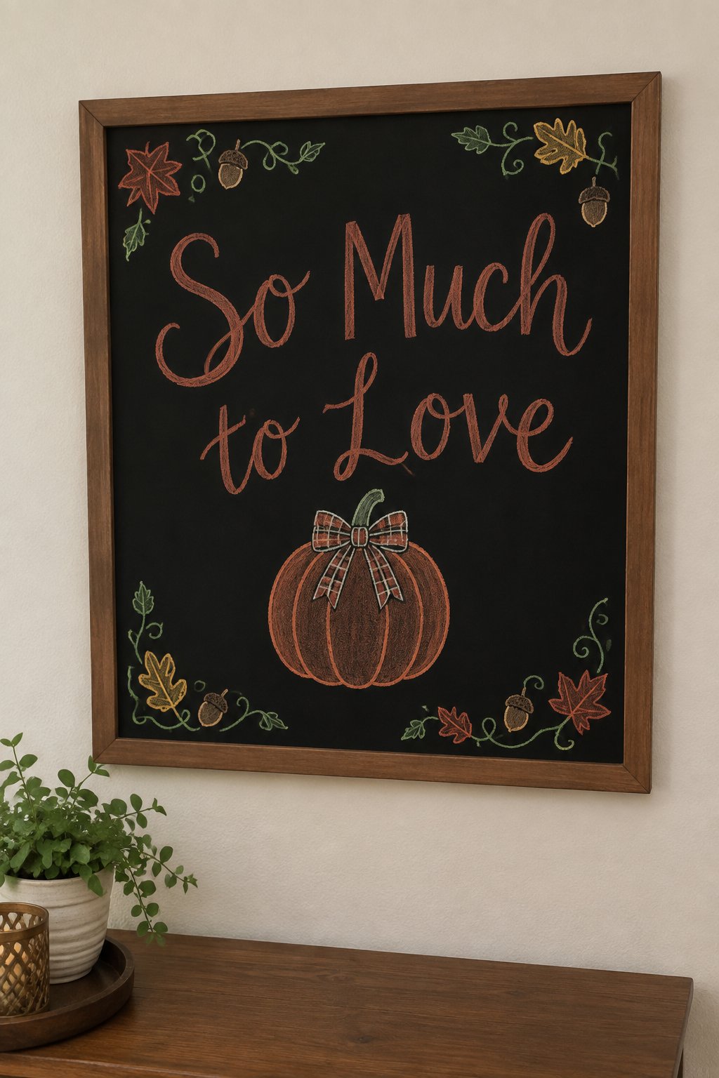 Pumpkin with a Bow: a framed fall chalkboard sign reading "So Much to Love", hand-drawn in chalk with one round pumpkin wearing a plaid bow on its stem.